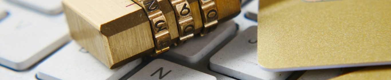 Zahlenschloss auf einer Computer-Tastatur neben einem Bleistift und einem Block.